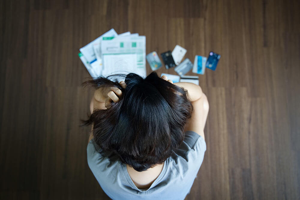 Stressed person looking down at all of their bills and credit cards